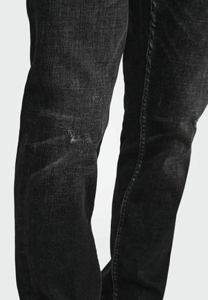 Mustad denim püksid sirge lõikega, kerge kulumise ja kulunud detailidega põlvedel. Õmmeldud õmblused ja klassikaline viie-tasku disain.