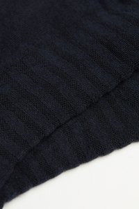 Marine gebreide stof met een gestructureerd ribbelpatroon, waarin overlappende lagen en fijne vakmanschap zichtbaar zijn. Zacht materiaal met een lichte glans.