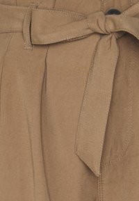 Ceinture en tissu marron avec un design noué. Texture lisse, bords cousus et plis. Comprend une boucle pour un maintien sécurisé.