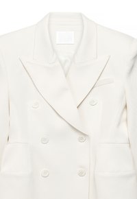 Hvid dobbeltradet blazer med markante spidse revers, to forlommer og seks knappelukninger. Tekstureret stof med subtile linjer.