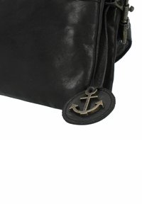 Bolso de cuero negro con una textura suave, que presenta un acento de ancla de bronce en una etiqueta circular de cuero y un cierre zip.