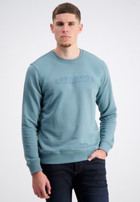 Blauw-groene sweatshirt met een ronde hals, ribgebreide boorden en zoom. Heeft een subtiele merklogo op de borst in een tonale uitvoering.