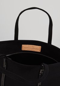 Borsa tote in tessuto nero con due manici, dotata di chiusura con zip e un'etichetta in pelle beige all'interno, contrassegnata "Le Cabas vanessabruno."