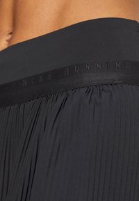 Svarta löparshorts med textilerad yta och veck, smidig midja och präglad "NIKE RUNNING"-logotyp på bandet.