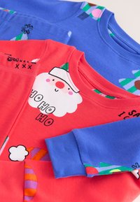 Deux sweat-shirts empilés ; l'un corail avec un motif du Père Noël et du texte, l'autre bleu avec des motifs colorés et des accents verts, tous deux en tissu doux.