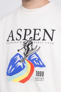 Sudadera de algodón blanca con un audaz texto en negro "ASPEN", un gráfico de esquí con montañas, un camino en arcoíris y el texto "1999 KAOTIKO SOCIETY".