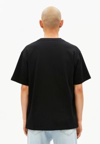 Zwart katoenen T-shirt met een ontspannen pasvorm en korte mouwen, met een klein logo op de achterkant. Gladde textuur en effen kleur.