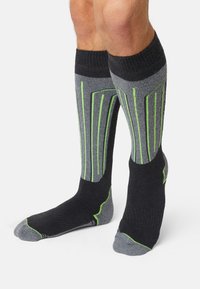 Knee-high athletic socks in black and gray with green accents. Features vertical line patterns, cushioned sole, and reinforced heel.