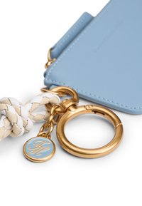 Portachiavi in pelle azzurro chiaro con cinturino intrecciato bianco e beige, ferramenta dorata e un ciondolo circolare con sfondo blu e iniziali.