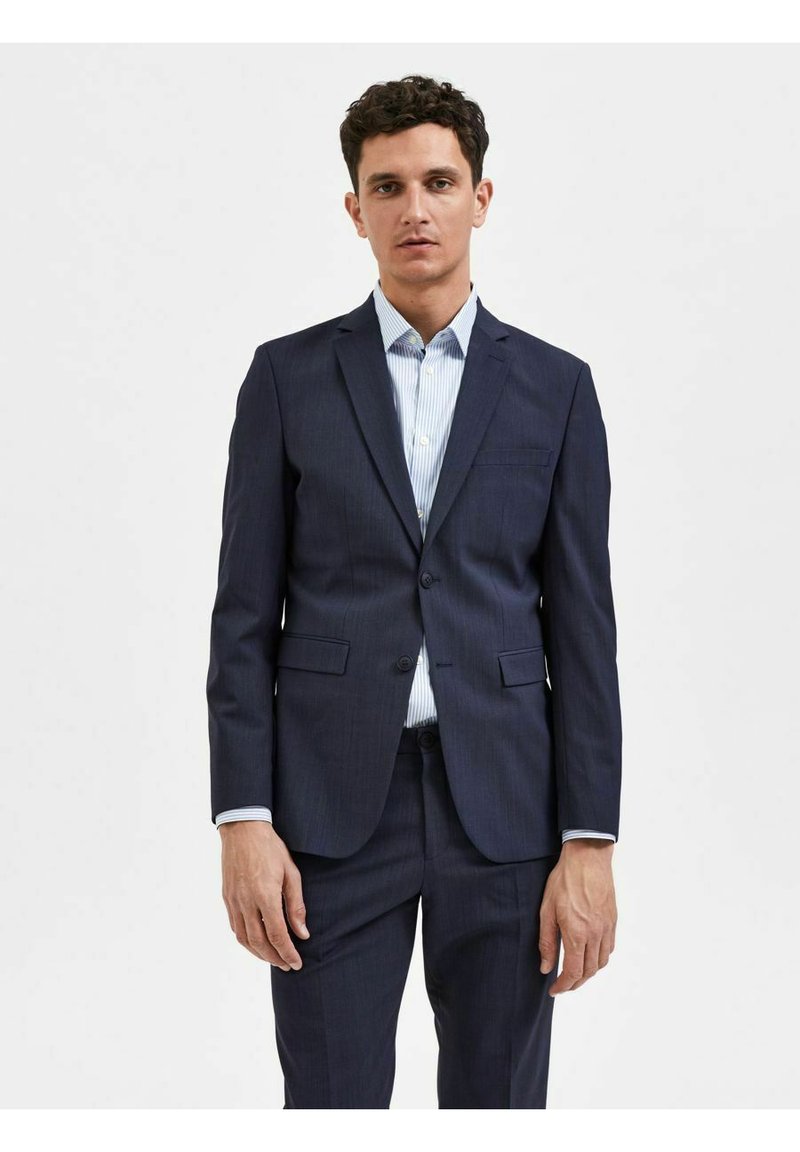 Marineblå dress med et pinstripe-mønster, en-knaps lukking, to frontlommer og en lyseblå stripete skjorte under.
