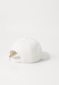 Fehér pamut baseballsapka ívelt napszemüveggel, állítható pánttal a hátsó részen, és hat szellőzőlyukkal. Nincsenek látható logók vagy minták.