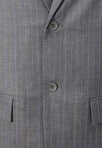 Gray pinstripe blazer featuring two buttons, notched lapels, two front pockets, and a textured fabric finish.