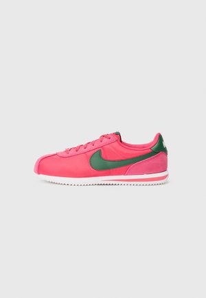 Baskets Nike roses avec des accents verts, présentant un dessus en textile lisse, un design à lacets et une semelle en caoutchouc blanc avec des rainures.