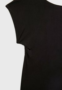 Gros plan sur un haut sans manches noir avec un design d'épaule large et un détail subtil de couture latérale sur un fond clair.