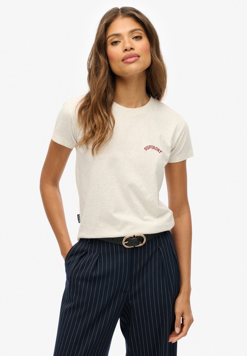Jasnoszara bawełniana koszulka z krótkim rękawem z czerwonym napisem "SUPERDRY". Połączona z granatowymi spodniami w paski i czarnym paskiem z złotą klamrą.