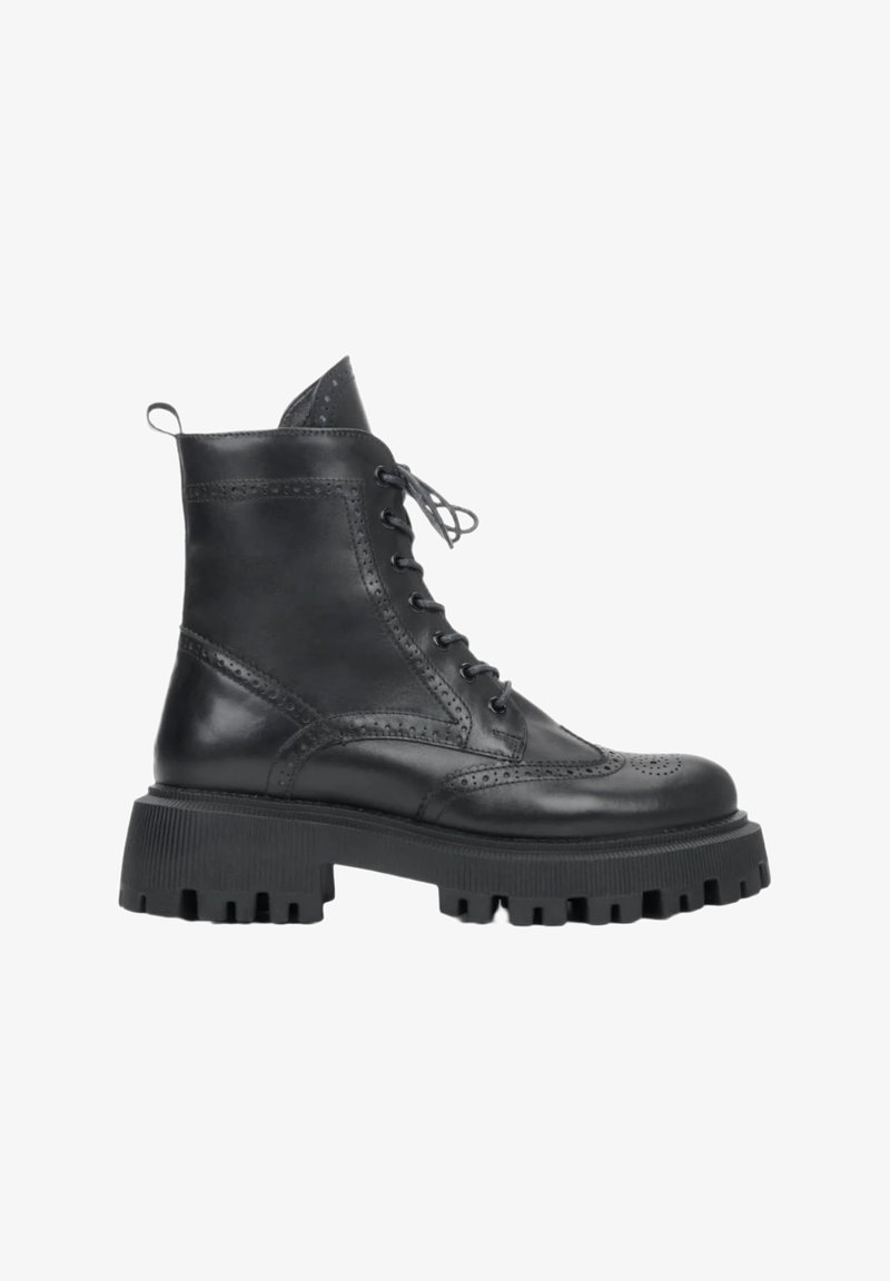 Black leather lace-up ankle boot with brogue detailing and thick ridged sole, side view on a white background.