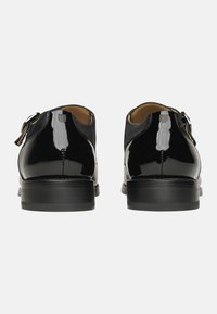 Schwarze Lederschuhe mit glänzender Oberfläche, mit glattem Material, abgerundeter Spitze und einer einzelnen silbernen Schnalle an der Seite. Niedriger schwarzer Absatz.