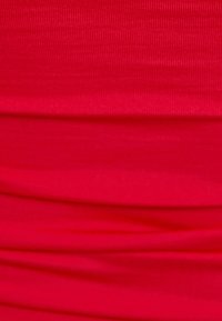 Czerwona elastyczna tkanina z ryflowanym wzorem, z marszczonymi liniami i fałdami. Materiał wydaje się gładki, o jednolitym, intensywnym kolorze.