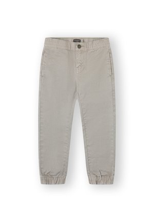 Pantalones infantiles de color beige claro con puños elásticos, bolsillos delanteros, cierre con botón y etiqueta de marca visible en el interior de la banda de la cintura.