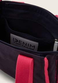 Borsa in tela nera con manici rosa, dotata di chiusura con zip e tasca interna. L'etichetta all'interno riporta "IDENIM TOM TAILOR."