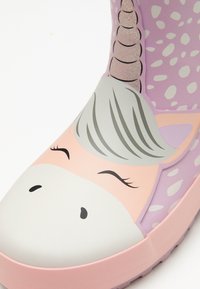 Bottes de pluie en caoutchouc avec un thème de licorne rose et violette, dotées d'une surface texturée, affichant un visage souriant, une corne pailletée et des motifs abstraits blancs.
