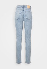 Světle modré džínové kalhoty s přiléhavým střihem, rovnými nohavicemi, dvěma zadními kapsami a koženou nášivkou na pase s logem. Hladká textura.