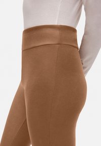 Leggings marrones de tiro alto con una textura suave, diseño ajustado y costuras mínimas, ideales para uso casual o deportivo.