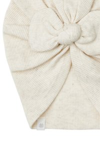 Un bandeau en ribbed de couleur crème avec un grand nœud au centre. En tissu doux avec une texture subtile, il présente une petite étiquette logo sur le côté.