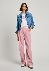 Jeansjacka, vit grafisk t-shirt, röd och vit randig vidbyxor, beige skor; avslappnad outfit med kontrasterande färger och mönster.