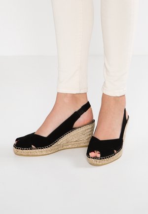 Czarne sandały na koturnie z tkaniny, z krzyżującymi się paskami, odkrytymi palcami oraz plecioną platformą z juty. Tylny pasek z elastycznym dopasowaniem.