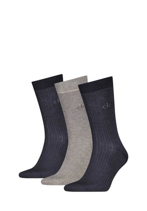 Tre paia di calzini alla caviglia: uno blu navy con motivo a pois, uno grigio chiaro e uno grigio scuro, tutti con bordi a coste e superficie liscia.