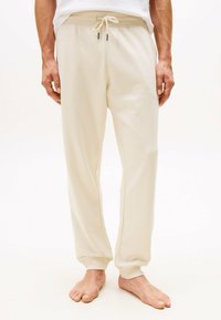 Joggers de algodón beige con cintura ajustable y puños acanalados, y costuras laterales. Textura suave con un corte relajado, adecuado para ropa casual.