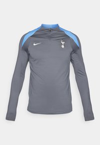 Graues Sportoberteil mit langen Ärmeln und einem Viertelreißverschluss, mit blauen Schulterakzenten und einem weißen Nike-Logo sowie einem Spurs-Wappen auf der Brust.
