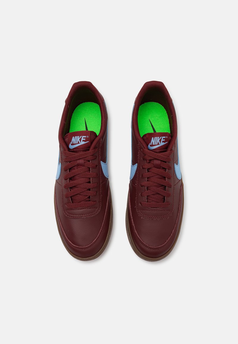 Zapatillas Nike de cuero burdeos con detalles en azul claro. Las características incluyen puntera redonda, cordones planos y plantillas verdes con el logo.