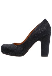 Zapato de tacón alto azul oscuro con superficie texturizada, puntera redondeada y tacón cuadrado. Presenta un sutil patrón de cruces que añade un detalle adicional.