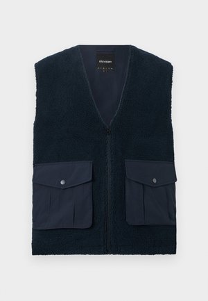 Γιλέκο από φλις σε ναυτικό μπλε με φερμουάρ εμπρός και δύο μεγάλες τσέπες με καπάκι και κουμπιά με κλιπ σε κάθε πλευρά.