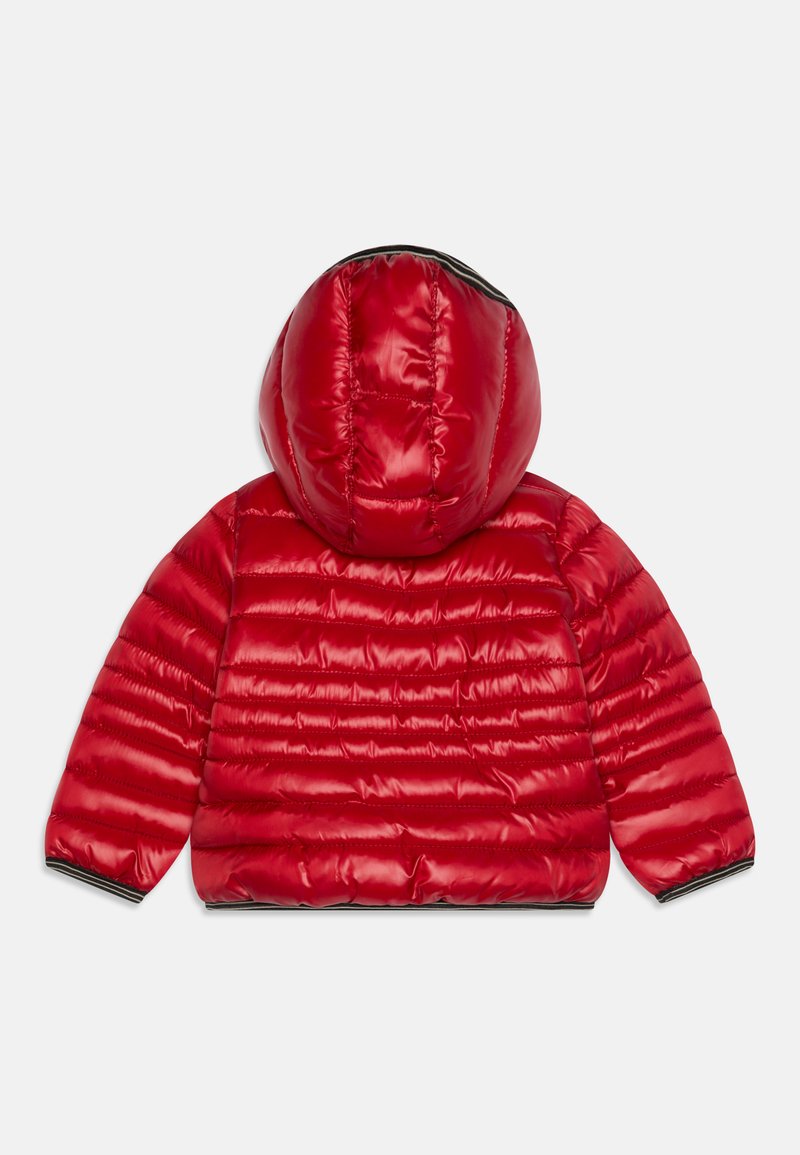 Giacca a vento rossa con cappuccio, realizzata in materiale lucido, con texture trapuntata e polsini elastici. Dettagli neri all'orlo e ai polsini.