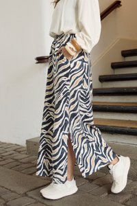 Maxi skirt with a blue, black, and beige zebra print. Features a high slit and a comfortable waistband. Paired with white sneakers.