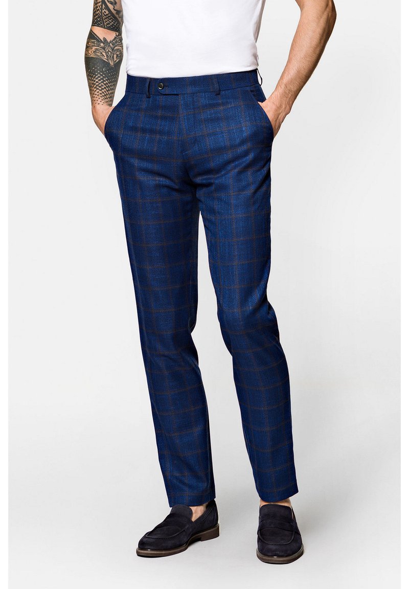 Niebieskie spodnie w kratę z teksturowanej tkaniny, o dopasowanym kroju, z paskami na pasek i zapięciem na guzik, zestawione z ciemnymi butami wsuwanymi.