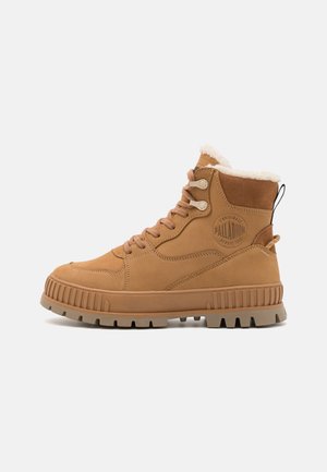 Bottes montantes en suede marron avec doublure en fourrure, semelle en caoutchouc et patch de logo, dotées d'œillets renforcés et de lacets plats.