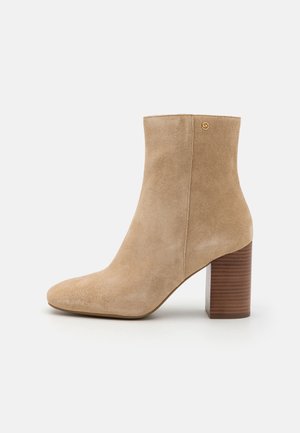 Bež sametist kõrge saapad, ümarate varvastega, sileda viimistlusega ja ribakujulise puidust plokk-kandaga. Taustal on peen logo aksent.