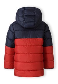 Vadderad jacka med en blå ovandel, röd nederdel och en huva. Kvadderad design med horisontella ränder och elastiska ärmslut.