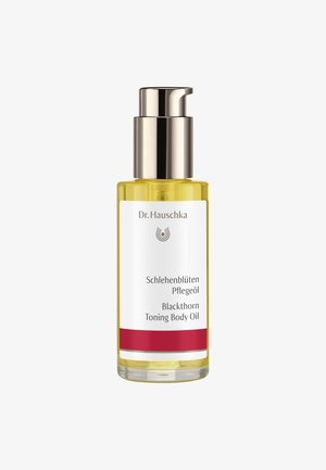 Transparente Glasflasche mit einer metallischen Pumpenoberseite, gefüllt mit gelbem Körperöl. Das Etikett hat einen weißen Hintergrund mit schwarzem Text und roten Akzenten.