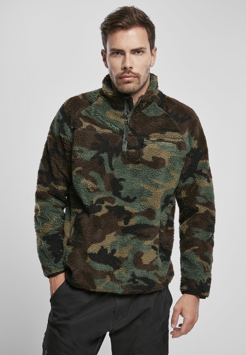 Sudadera de forro polar en un patrón de camuflaje con tonos marrones, verdes y negros; cuenta con un cierre de cuarto de cremallera en la parte delantera y un bolsillo en el pecho con cremallera.