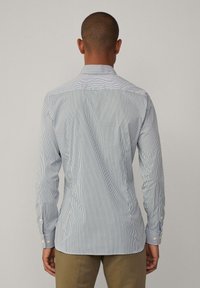 Camicia a righe blu e bianca, con colletto classico, maniche lunghe e vestibilità affusolata. Tessuto liscio con una leggera lucentezza.