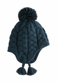 Stickad mössa i mörk teal med kabelmönster, har en stor pom-pom på toppen och tofsar i botten. Mjuk ulltextur.