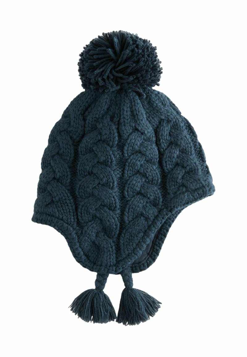 Stickad mössa i mörk teal med kabelmönster, har en stor pom-pom på toppen och tofsar i botten. Mjuk ulltextur.