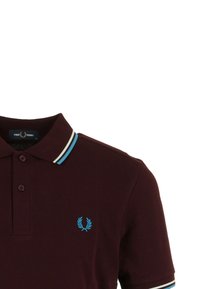 Burgundyröd polo skjorta i texturerat tyg, med en tvåknapps knäppning, kontrasterande blå och vit randig krage, samt en logotyp på bröstet.