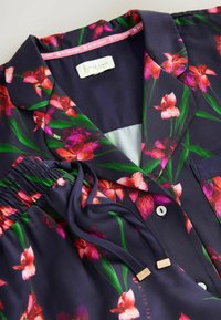 Navy bloemen pyjama set met roze en groene bloemmotieven, satijnen textuur, kraag, knopen en een elastische taille met trekkoordaccenten.