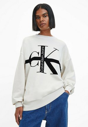 Sudadera de Calvin Klein Jeans en beige claro con un gran logo negro. Presenta un corte de cuello redondo y un diseño de hombros caídos. Tejido de mezcla de algodón.